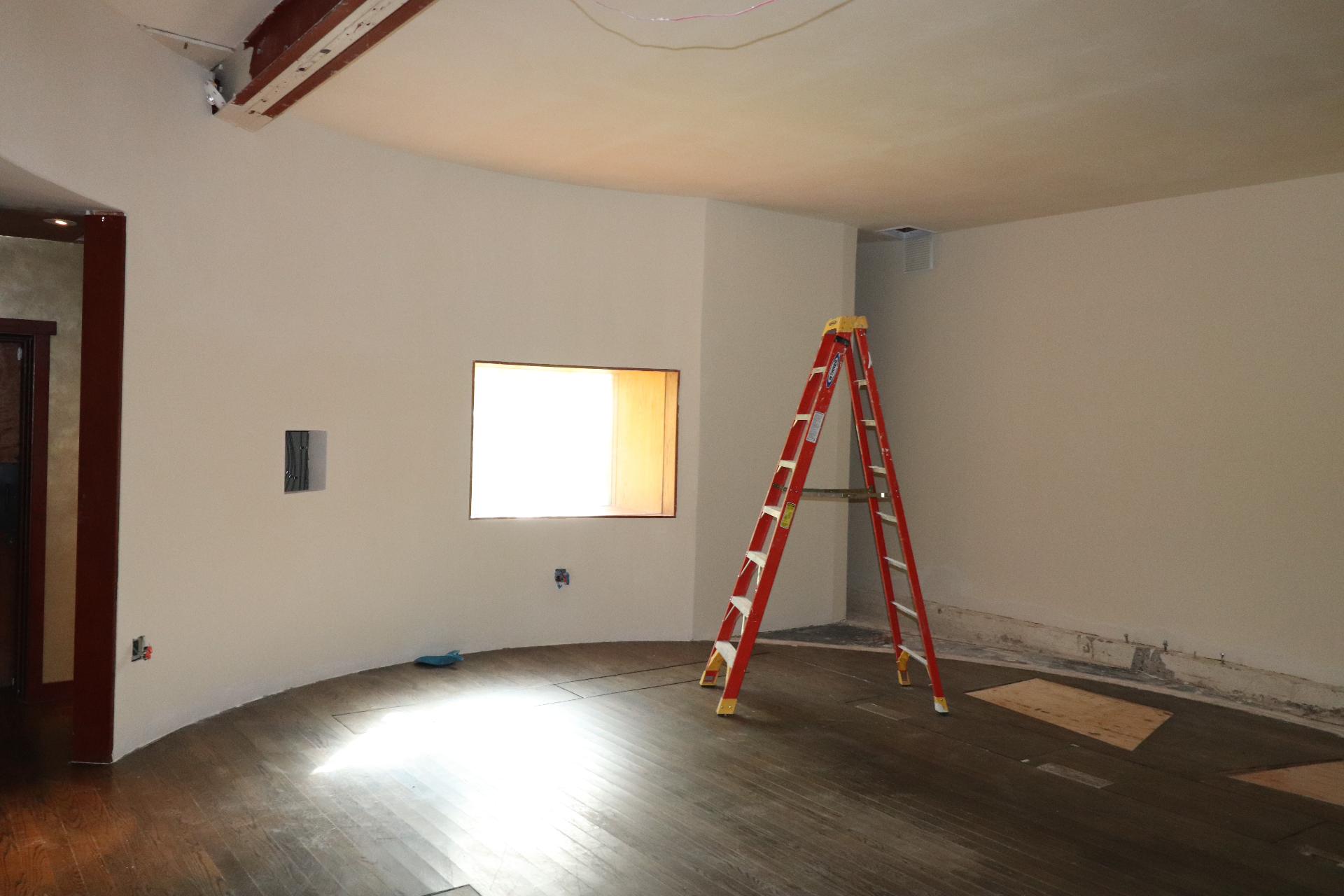 The Garden — curved oval room mid-renovation in 2026, with a ladder, exposed ceiling, and dark wood floor.