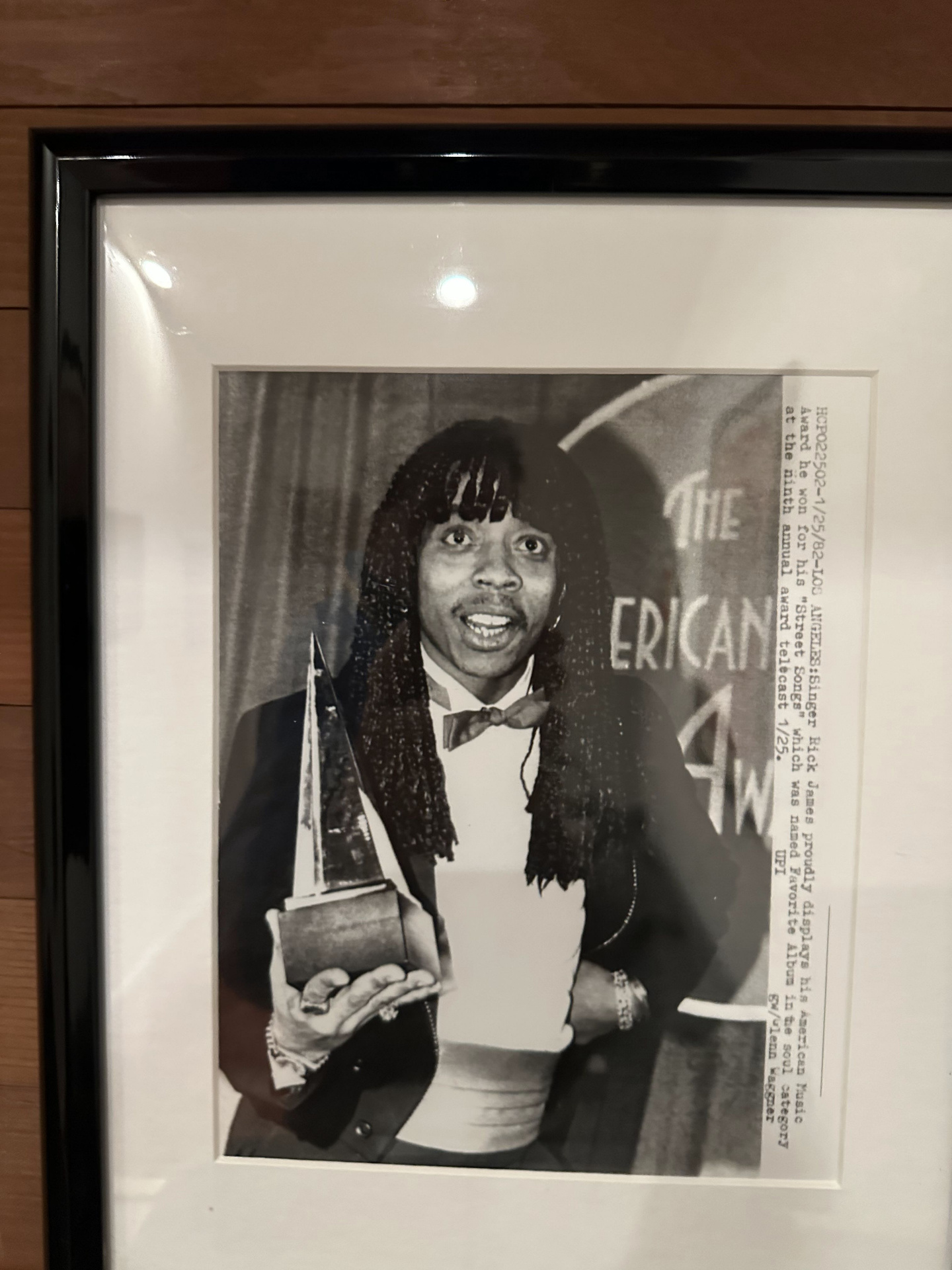 Framed UPI wire photo of Rick James holding his American Music Award for Street Songs, January 1982.