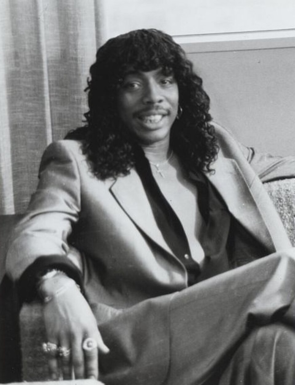 Rick James seated in a satin suit, smiling, from a 1984 episode of Lifestyles of the Rich and Famous.