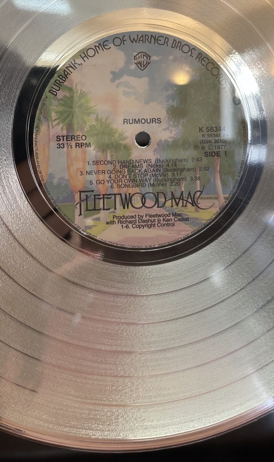 Close-up of a platinum record award showing the Side 1 label of Fleetwood Mac's Rumours, with 'DREAMS (Nicks) 4.14' visible in the tracklist.