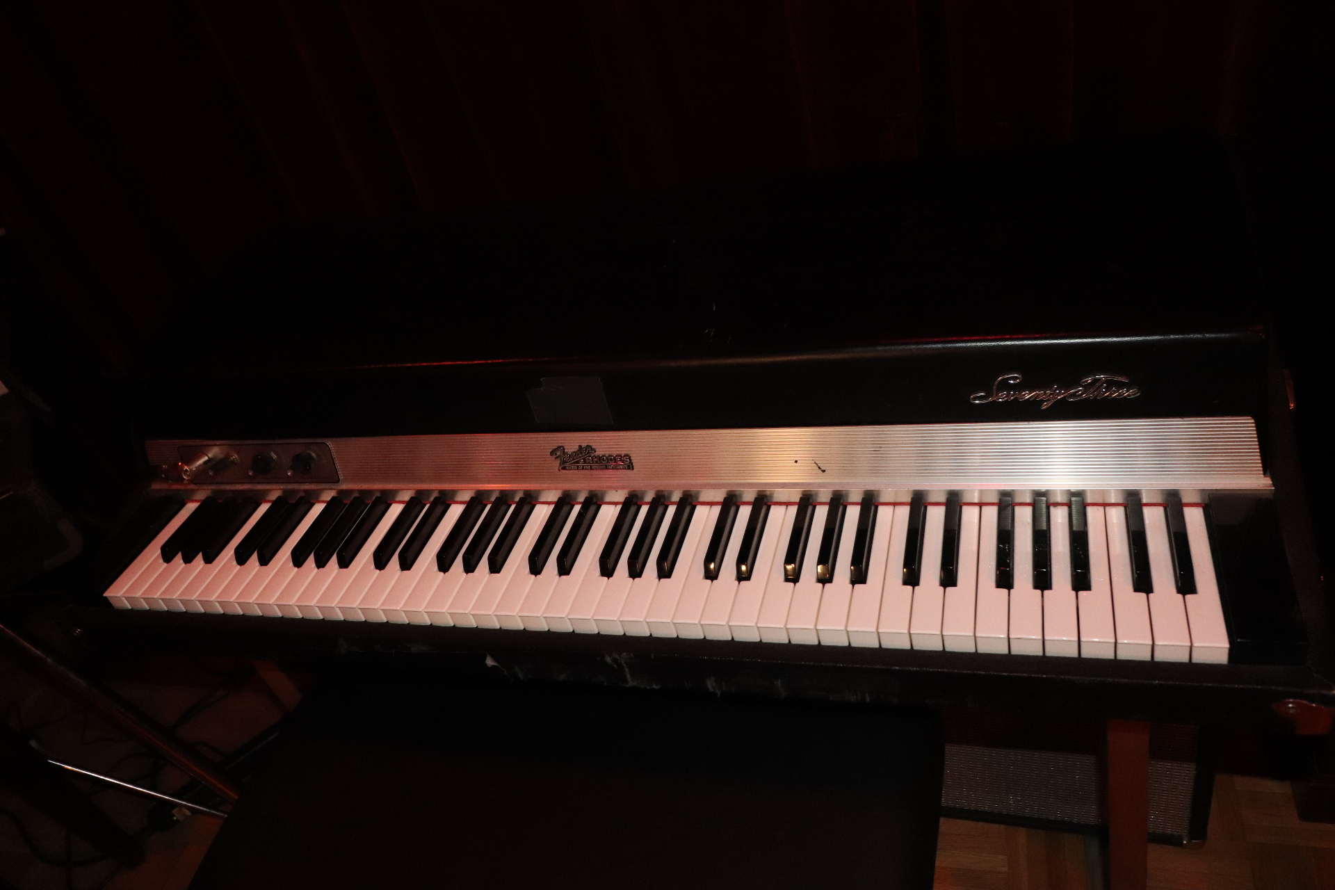 Fender Rhodes Seventy Three electric piano on its stand in Studio B, lit warmly against the dark red wall.