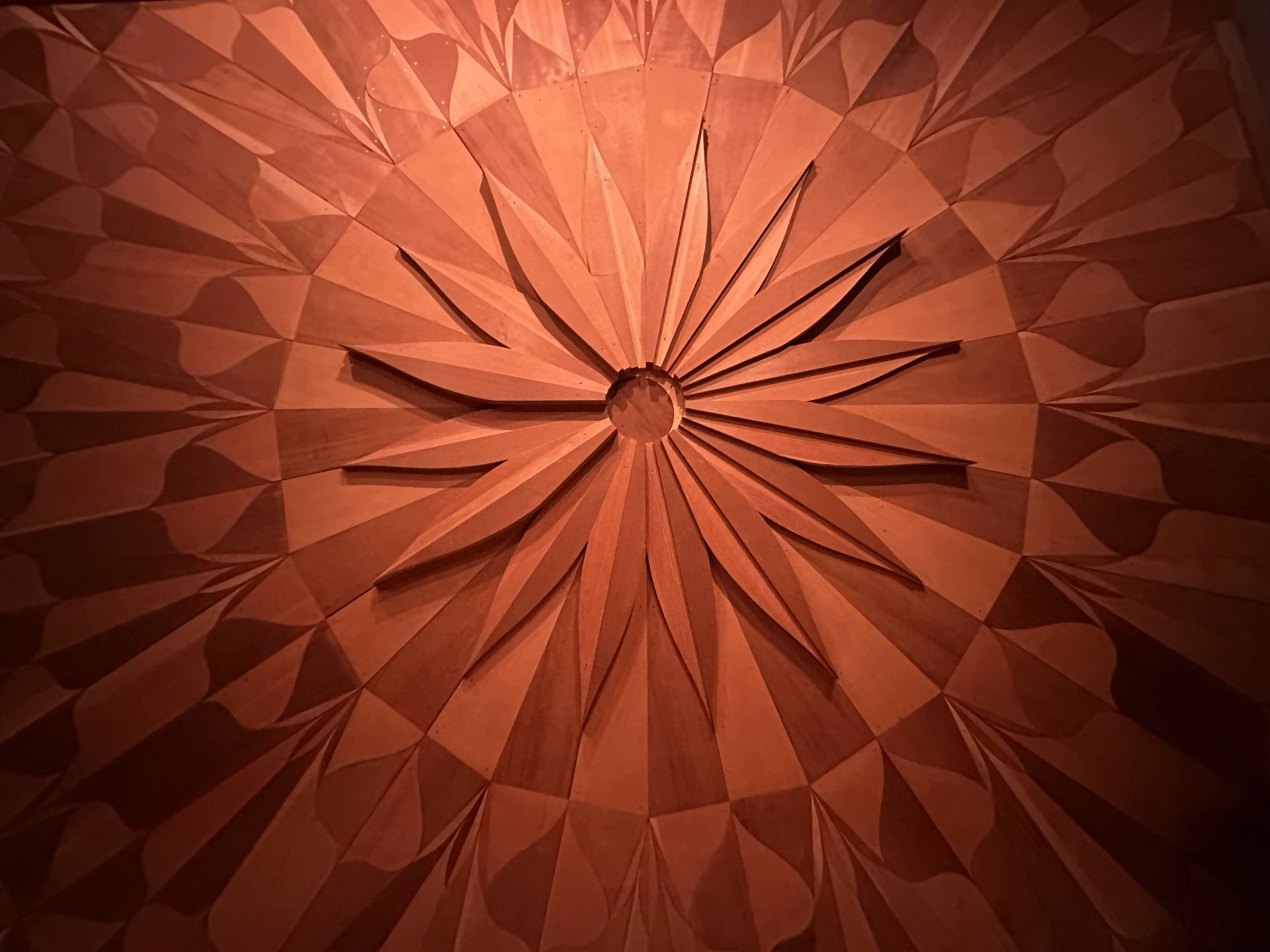 Carved redwood sunburst — the iconic Studio A wall pattern radiating from a central hub in concentric petals.